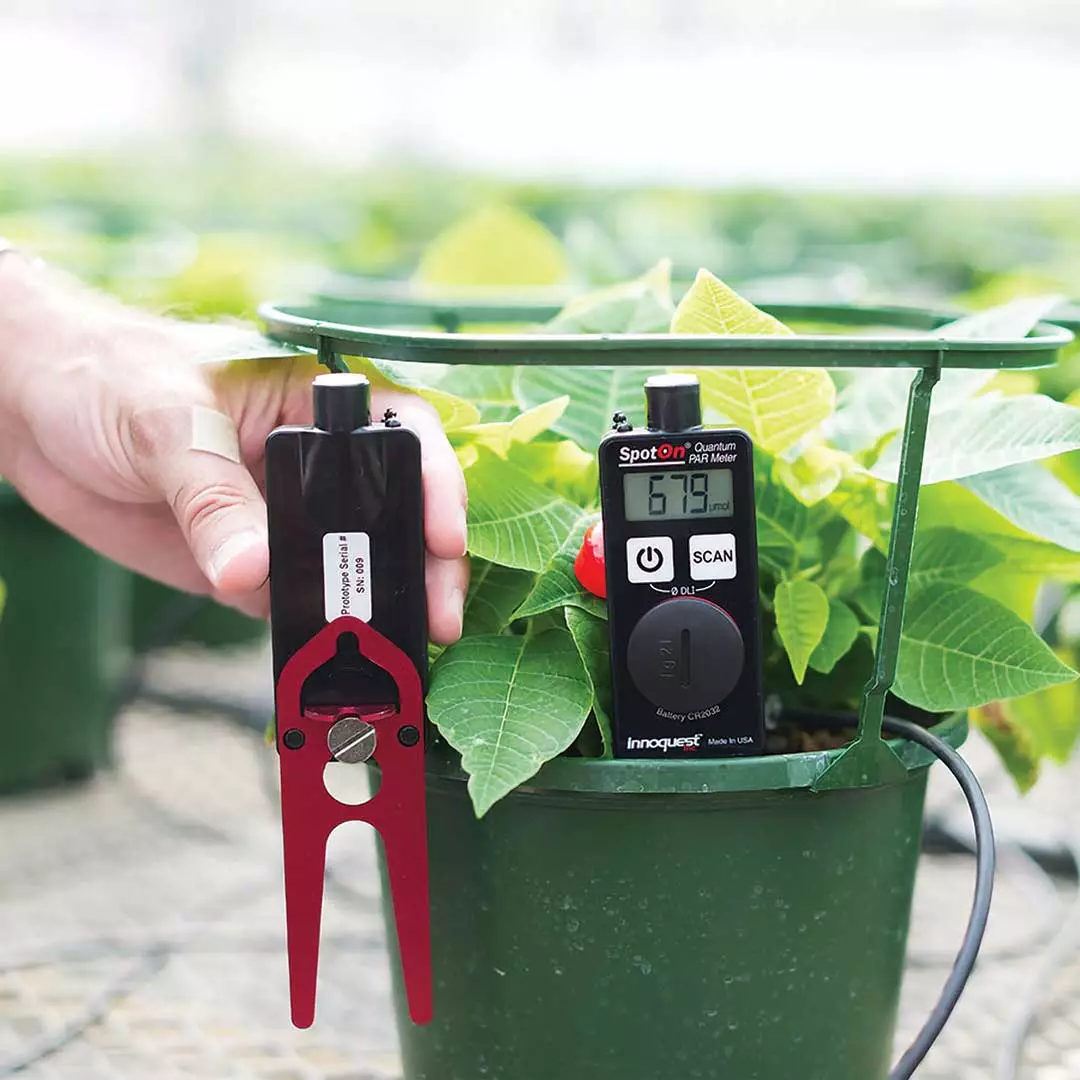 meter in plant pot with man holding second meter