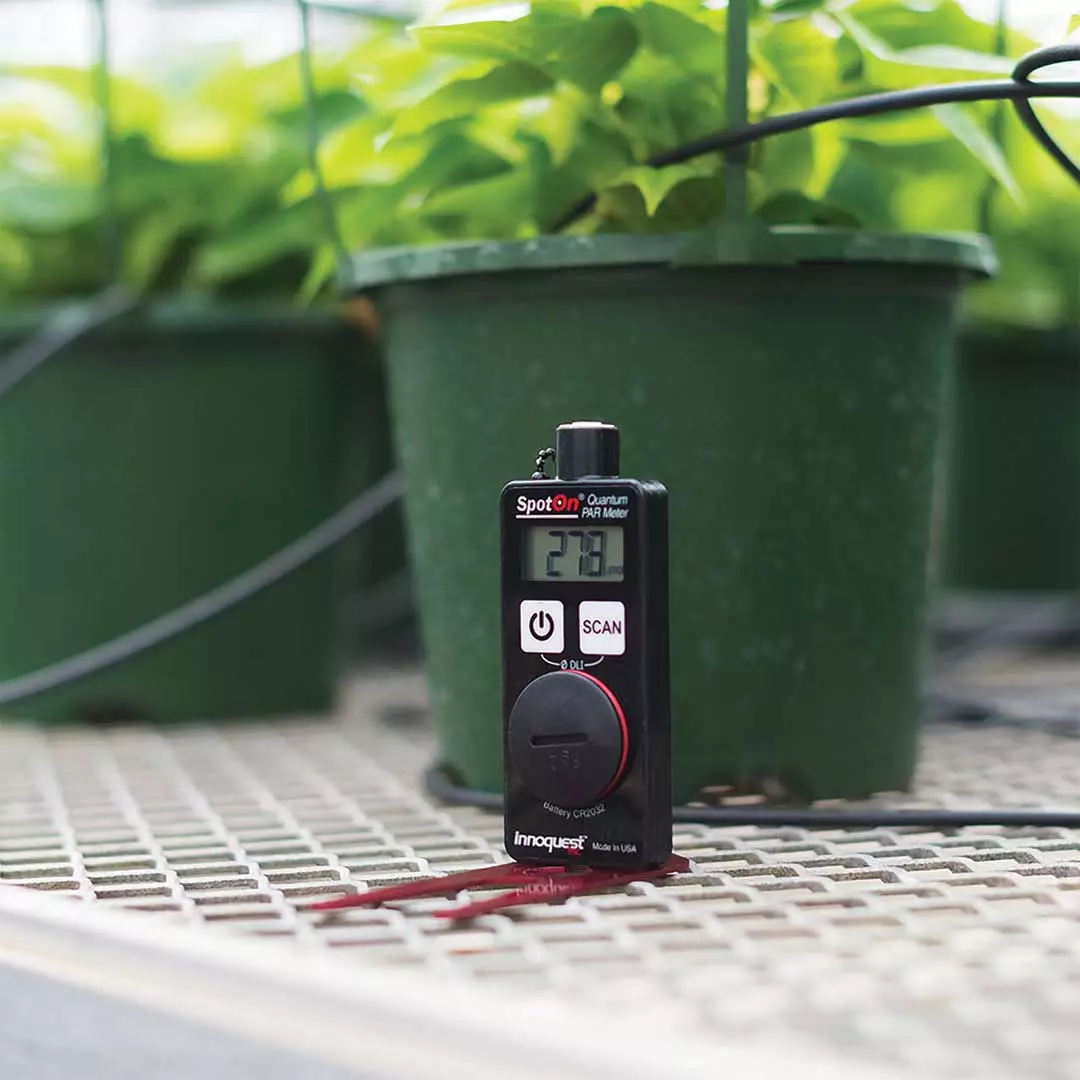 meter sitting on base in front of plant pot